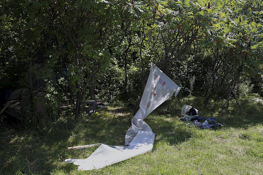 6. Refuse from encampment containing couch, coffee table, and boards hung from trees and used for a clothing line, East London, August 2014