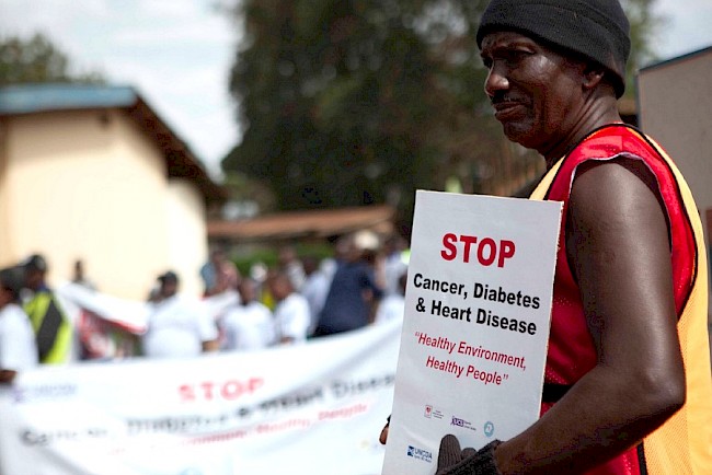 Mike of the Uganda NCD Alliance leads a parade around the community in Kampala to raise awareness of NCDs (photo credit: WHO/A Wang)