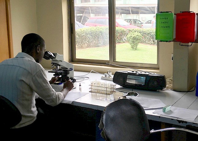 6. Analyzing a blood smear for malarial parasites, Kumasi South Hospital. Agogo-Kumasi, Ashanti Region, Ghana, 2018.